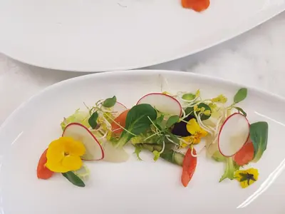 a plate of food with vegetables and flowers on it at Hotel Thuinerwaldele in Vipiteno