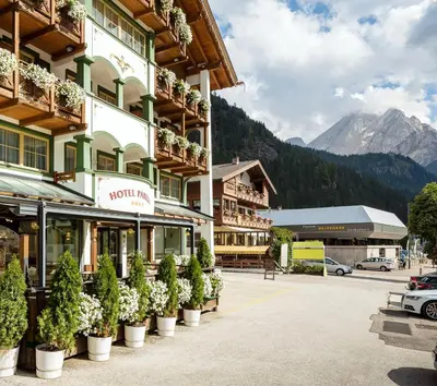 a hotel with potted plants in a parking lot at Hotel Pareda in Canazei