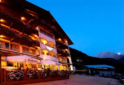 a building with tables and umbrellas in front of it at Hotel Pareda in Canazei