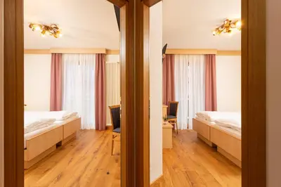 a hotel room with two beds and a mirror at Hotel Pareda in Canazei