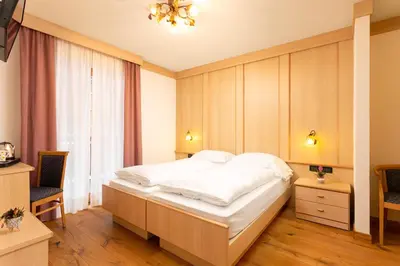 a bedroom with a large white bed and a window at Hotel Pareda in Canazei