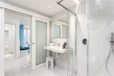 a white bathroom with a sink and a shower at Hotel Pareda in Canazei
