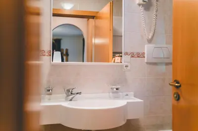 a bathroom with a white sink and a mirror at Garni Hotel Belalp in Santa Cristina in Val Gardena