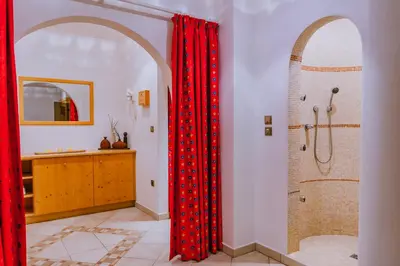 a bathroom with a shower and a red shower curtain at Garni Hotel Belalp in Santa Cristina in Val Gardena
