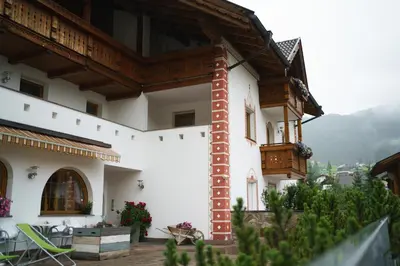 a large white building with a balcony and a table at Garni Hotel Belalp in Santa Cristina in Val Gardena