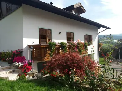 a white house with flowers and a balcony at Appartamento Cologna in Castelfondo