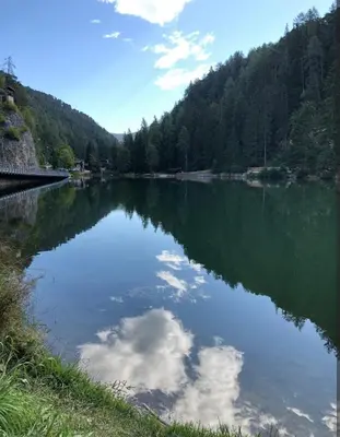 a river with a reflection of a cloud in the water at Appartamento Cologna in Castelfondo