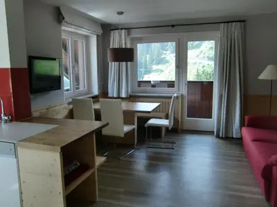 a living room with a table and a red couch at Prà de Metz Apartments in Santa Cristina in Val Gardena