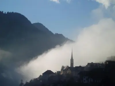 a city in the fog with a church in the background at Prà de Metz Apartments in Santa Cristina in Val Gardena