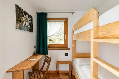 a bedroom with a desk and a bunk bed at B&B Sot l'Agner - Ospitalità Diffusa Conca Agordina in Taibon