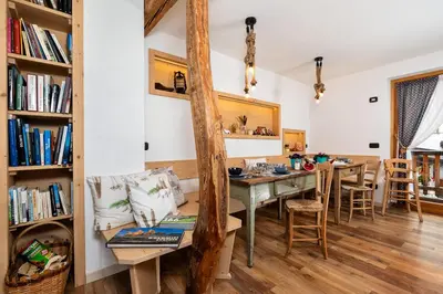 a dining room with a table and chairs and bookshelves at B&B Sot l'Agner - Ospitalità Diffusa Conca Agordina in Taibon
