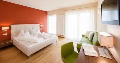 a bedroom with a white bed and a green couch at Hotel Residence Pernhof in Termeno