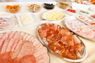 a table filled with different types of meats and cheeses at Hotel Residence Pernhof in Termeno