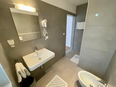 a bathroom with a sink and a mirror and a toilet at Transit Rooms - Your Stopover, Free Parking in Vipiteno
