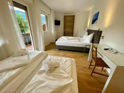 a hotel room with two beds and a desk with a desk at Transit Rooms - Your Stopover, Free Parking in Vipiteno