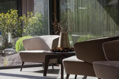 a vase sitting on a table next to two chairs at Klein Fein Hotel Anderlahn in Parcines