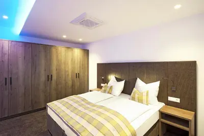 a bedroom with a large bed with a wooden headboard at Hotel Sonnenhof in Marlengo