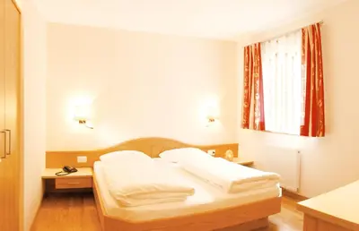 a bedroom with a bed with white sheets and a window at Hotel Sonnenhof in Marlengo