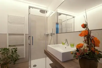 a white bathroom with a sink and a shower at Hotel Sonnenhof in Marlengo