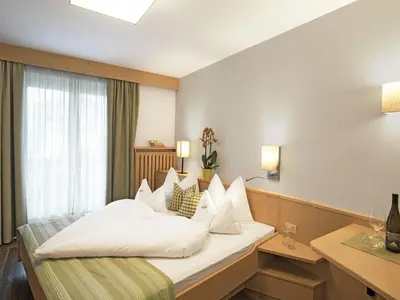 a hotel room with a large bed with white pillows at Hotel Sonnenhof in Marlengo