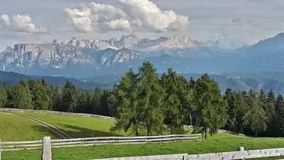 a pasture with a fence and mountains in the background at Kastnerhof in Meltina