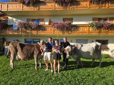 a group of people standing in a field with two cows at Kastnerhof in Meltina