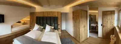 a bedroom with a large white bed and wooden walls at Apartments Pitschlmann in Fiè