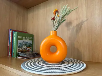 an orange vase with flowers in it sitting on a table at Haus Santner in Fiè