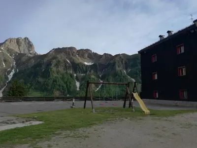 a playground in front of a building with a mountain at Piccolo Igloo in Falcade