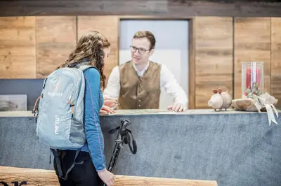 a woman standing in front of a counter with a man at Hotel Wieser in Campo di Trens