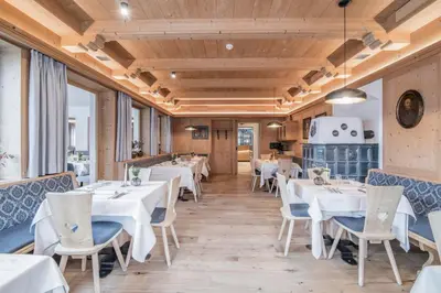 a restaurant with white tables and chairs and windows at Hotel Wieser in Campo di Trens