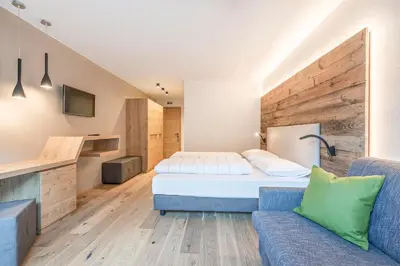 a hotel room with a bed and a couch at Hotel Wieser in Campo di Trens