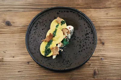 a black plate with food on a wooden table at Hotel Wieser in Campo di Trens