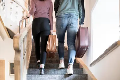 two people walking down the stairs with their luggage at Hotel Wieser in Campo di Trens