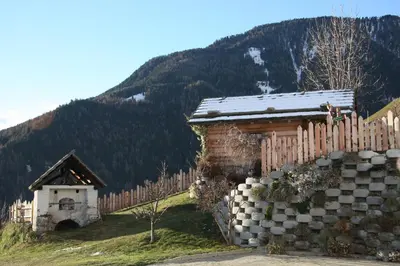 a small house with a fence and a mountain at Pirchnerhof in San Lorenzo di Sebato