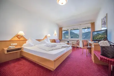 a hotel room with a large bed and a desk at Hotel Walter in Schenna