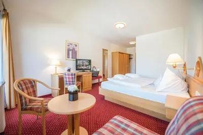 a hotel room with a bed and a chair at Hotel Walter in Schenna
