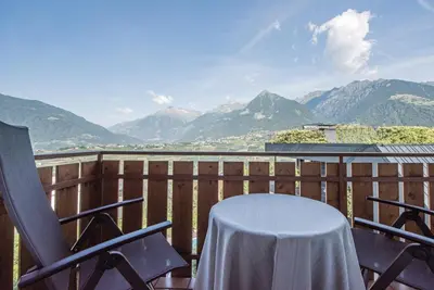 a table and chairs on a balcony with mountains at Hotel Walter in Schenna