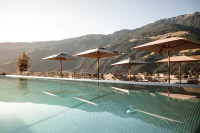 a swimming pool with umbrellas and tables and chairs at Sonnen Resort in Naturno