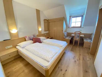 a bedroom with a large bed and a table at Lindnerhof Urlaub am Bauernhof in San Lorenzo di Sebato