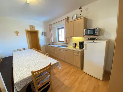 a kitchen with a table and a white refrigerator at Lindnerhof Urlaub am Bauernhof in San Lorenzo di Sebato