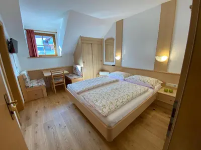 a small bedroom with a bed and a table at Lindnerhof Urlaub am Bauernhof in San Lorenzo di Sebato