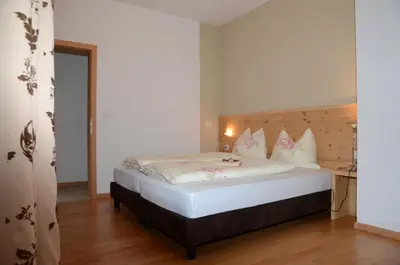 a bedroom with a bed with white sheets and pillows at Villa Grünewald in Siusi