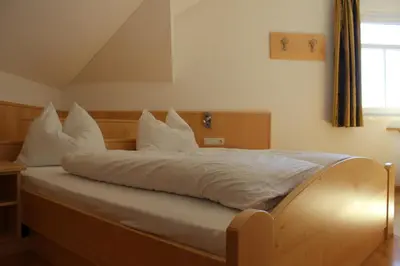 a bedroom with a bed with white sheets and pillows at Villa Grünewald in Siusi