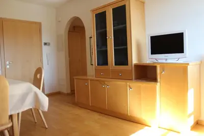 a living room with a television on a wooden cabinet at Villa Grünewald in Siusi