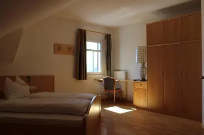 a bedroom with a bed and a desk and a window at Villa Grünewald in Siusi