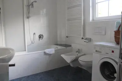 a white bathroom with a toilet and a sink at Villa Grünewald in Siusi
