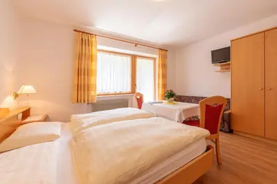 a hotel room with two beds and a table at Residence Trenker Luis in Braies