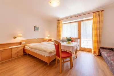 a bedroom with a bed and a table and a couch at Residence Trenker Luis in Braies