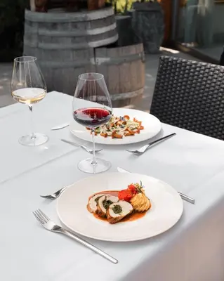 a table with two plates of food and wine glasses at Mineralienhotel Natznerhof in Naz-Sciaves
